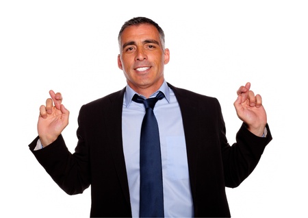 Portrait of a elegant executive man smiling and crossing the fingers on isolated backgroundの写真素材