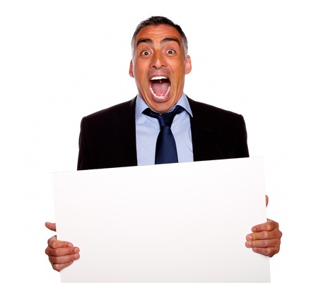 Portrait of a hispanic senior businessman screaming and holding a white card with copyspace on isolated backgroundの写真素材
