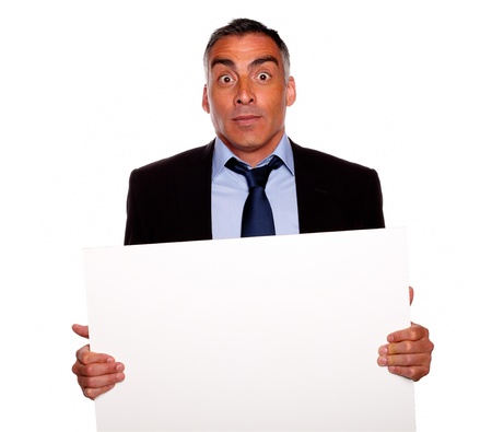 Portrait of a elegant surprised business man holding a white card with copyspace while having fun on isolated backgroundの写真素材