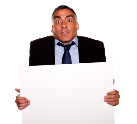 Portrait of a elegant surprised hispanic senior man holding a white card with copyspace on isolated backgroundの写真素材