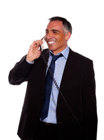 Portrait of a businessman speaking on phone while looking to right and wearing a black suit against white backgroundの写真素材