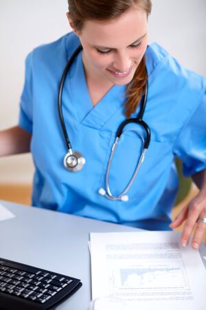 Portrait of a young beautiful nurse on blue uniform working at hospital officeの写真素材