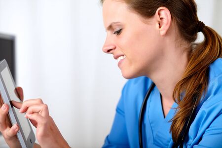 Portrait of a beautiful friendly nurse smiling with a tablet PC at hospital officeの写真素材
