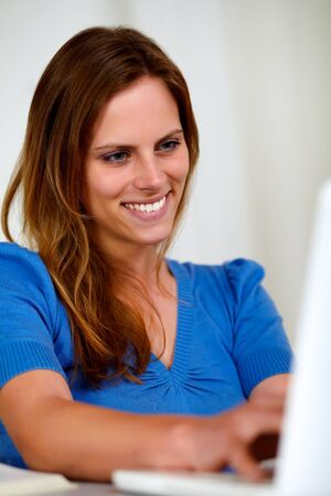 Portrait of a attractive woman writing on laptop at home indoorの写真素材