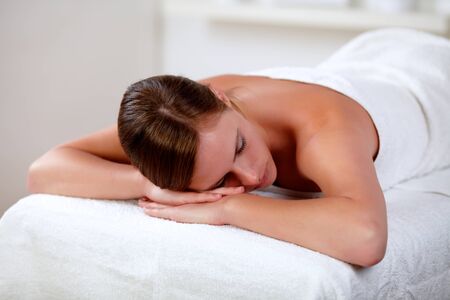 Portrait of a young woman lying on a stretcher at spa indoorの写真素材