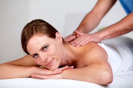 Close-up portrait of a pretty young blonde woman relaxing at a spa while receiving a massage at spa resort looking at youの写真素材