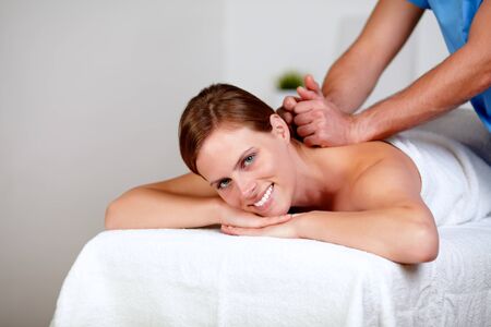 Portrait of a young female getting a back massage by a masseuse at spa resortの写真素材
