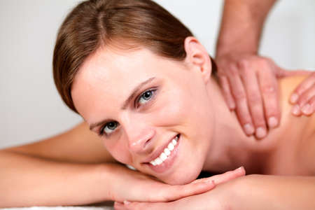 Close-up portrait of a lovely pretty woman smiling and relaxing while getting a massage from a professional masseuse at spaの写真素材