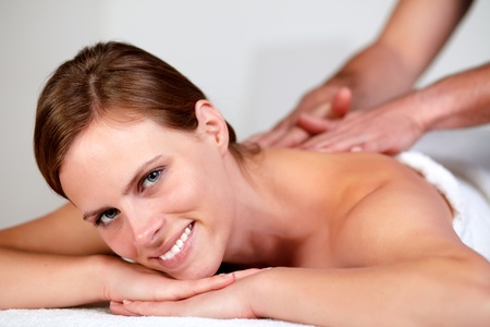 Close-up portrait of a young pretty woman smiling and relaxing while getting a massage from a professional masseuse at spaの写真素材
