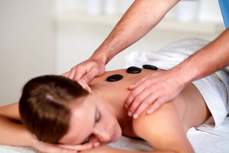 Close-up portrait of a young female relaxing at a day spa, hot stone massage treatmentの写真素材