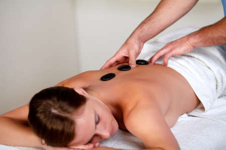 Close up of a beautiful woman getting a massage with hot stones at a spa resortの写真素材