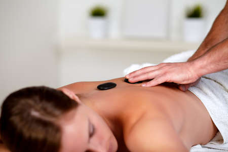 Close up portrait of a young woman getting a massage with hot stones at spa resortの写真素材