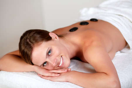 Close up portrait of a young girl smiling and relaxing at spa, hot stone massage treatmentの写真素材