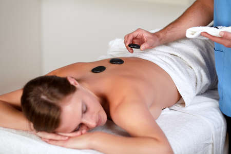 Close up of a woman relaxing while having a hot stone massage at a health spa resortの写真素材