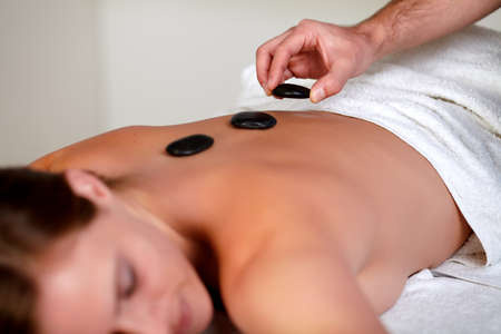 Close up of a young girl relaxing while having a hot stone massage at a health spa resortの写真素材