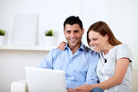 Portrait of a friendly couple having fun on laptop at home indoorの写真素材
