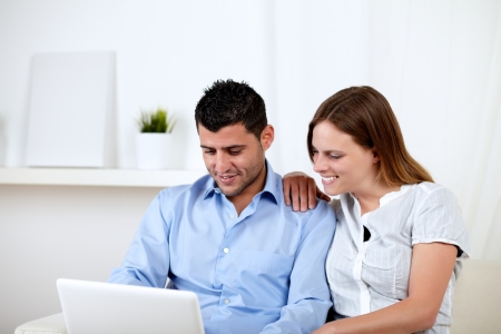 Portrait of a young woman with her ââboyfriend looking to laptop screen at home indoorの写真素材