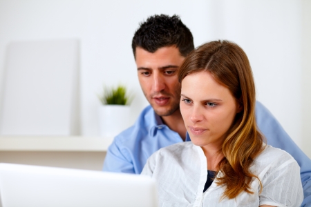 Portrait of a attractive young couple using laptop together at home indoorの写真素材