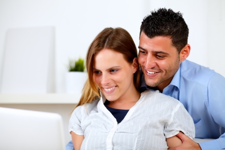 Portrait of a lovely young couple browsing Internet together on their laptop at home indoorの写真素材