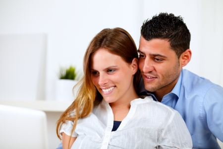 Portrait of a pretty couple in love using the laptop together at homeの写真素材