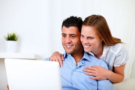 Portrait of a smiling young couple using laptop at home indoorの写真素材