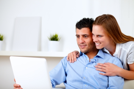 Portrait of a beautiful couple using laptop together at living room at home indoorの写真素材