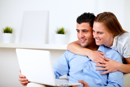 Portrait of a charming couple using laptop together at living room at home indoorの写真素材