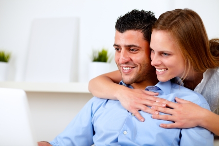 Portrait of a pretty young couple browsing Internet together on their laptop at living room at home indoorの写真素材