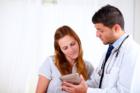 Portrait of a attractive hispanic doctor conversing with young woman at hospitalの写真素材
