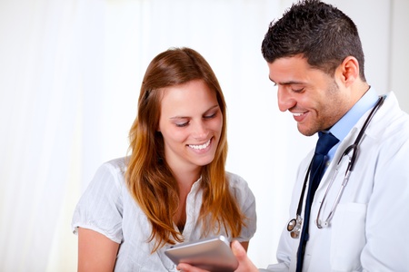 Portrait of a latin doctor and a patient woman looking something on tablet PC at hospitalの写真素材