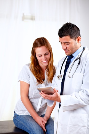 Portrait of a latin doctor and a female patient looking something on tablet PC at hospitalの写真素材