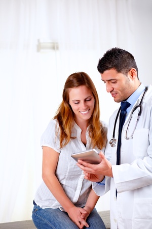 Portrait of a handsome doctor and a female patient looking something on tablet PC at hospitalの写真素材