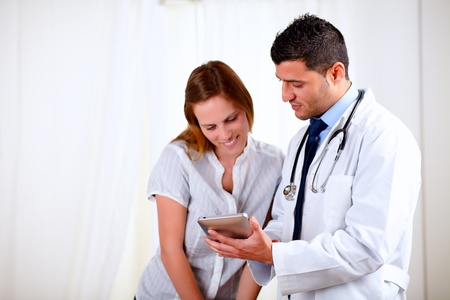 Portrait of a handsome doctor and a female patient looking something on tablet PC at hospitalの写真素材