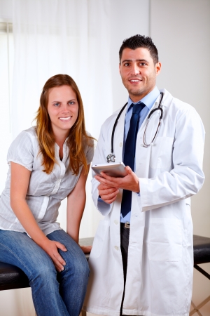 Portrait of a handsome medical doctor with a young patient woman standing on white uniform at hospital looking at youの写真素材