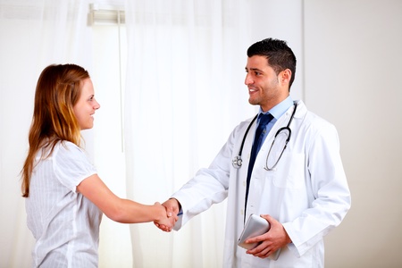 Portrait of a medical doctor smiling and greeting a pretty patient at hospital indoorの写真素材