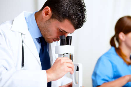 Portrait of a attractive latin doctor using a microscope at laboratory at hospital indoorの写真素材
