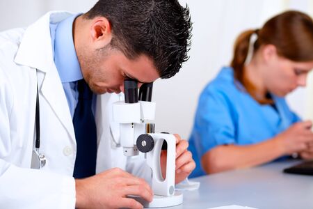 Portrait of two medical doctors working at laboratory at hospital using a microscopeの写真素材