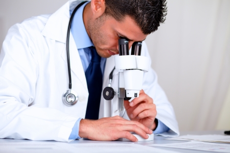 Portrait of a hispanic professional doctor with a microscope at laboratory at hospital indoorの写真素材
