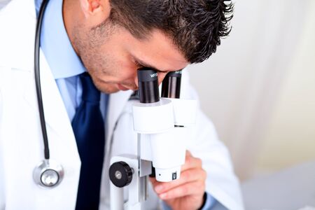 Portrait of a attractive latin doctor using a microscope at hospital indoorの写真素材