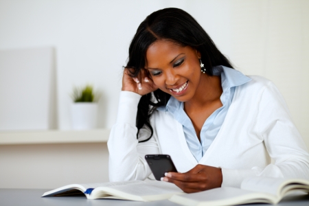 Portrait of a pretty lovely woman smiling and reading a cellphone message at soft colors compositionの写真素材