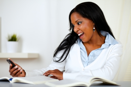 Portrait of a lovely young woman smiling and reading a cellphone message at home indoorの写真素材