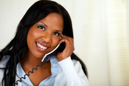 Close up portrait of a happy young female speaking on phone while looking up at soft colors compositionの写真素材