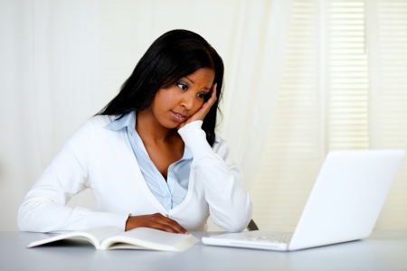 Portrait of a reflective young woman studying and looking to the laptop screen at soft colors compositionの写真素材