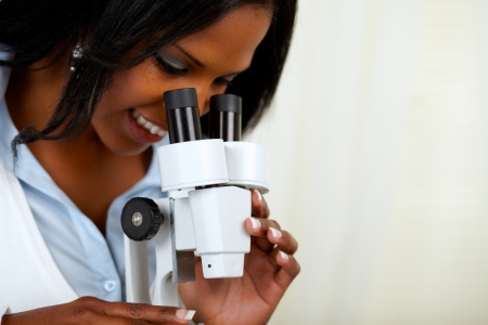 Portrait of a beautiful afro-american black woman using a microscope at soft colors compositionの写真素材