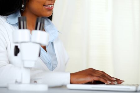 Portrait of a beautiful black young woman working on laptop at laboratoryの写真素材