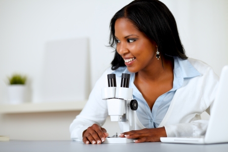 Portrait of a pretty black female working with a microscope at laboratoryの写真素材