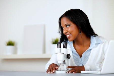 Portrait of a charming young woman using a microscope while looking to his rightの写真素材