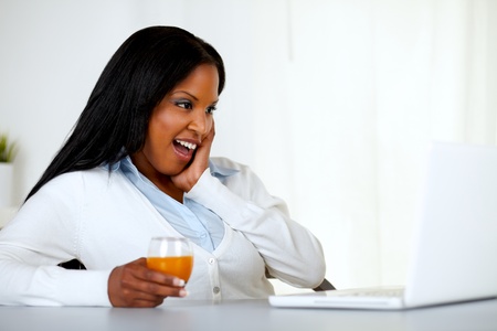 Portrait of a surprised young woman having fun on laptop screen at soft colors compositionの写真素材