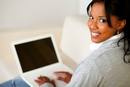 Portrait of a beautiful young woman working on laptop while is looking to youの写真素材