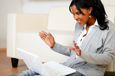 Portrait of an excited and surprised stylish woman looking to laptop screen while is sitting on the floor at homeの写真素材